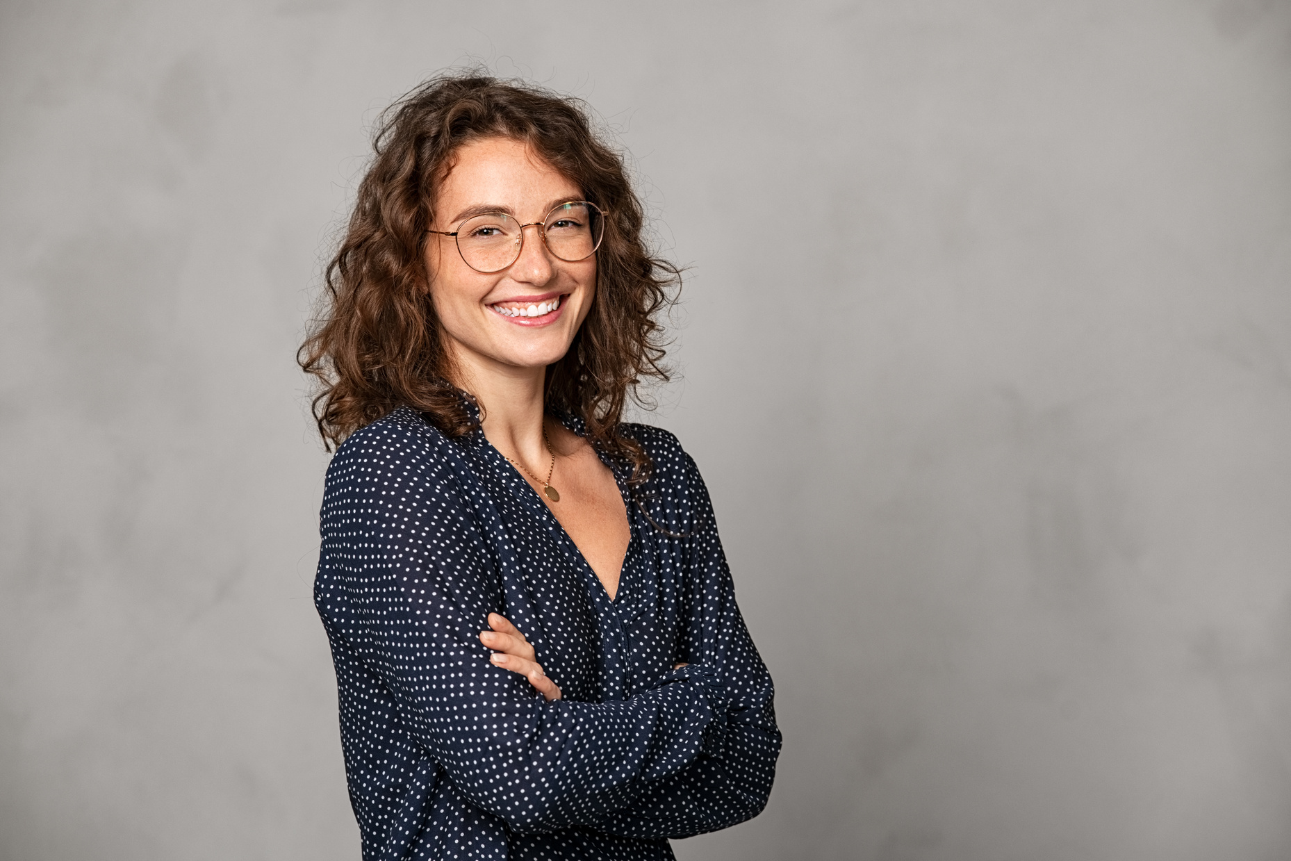 Smiling Woman Wearing Eyeglasses on Grey Wall